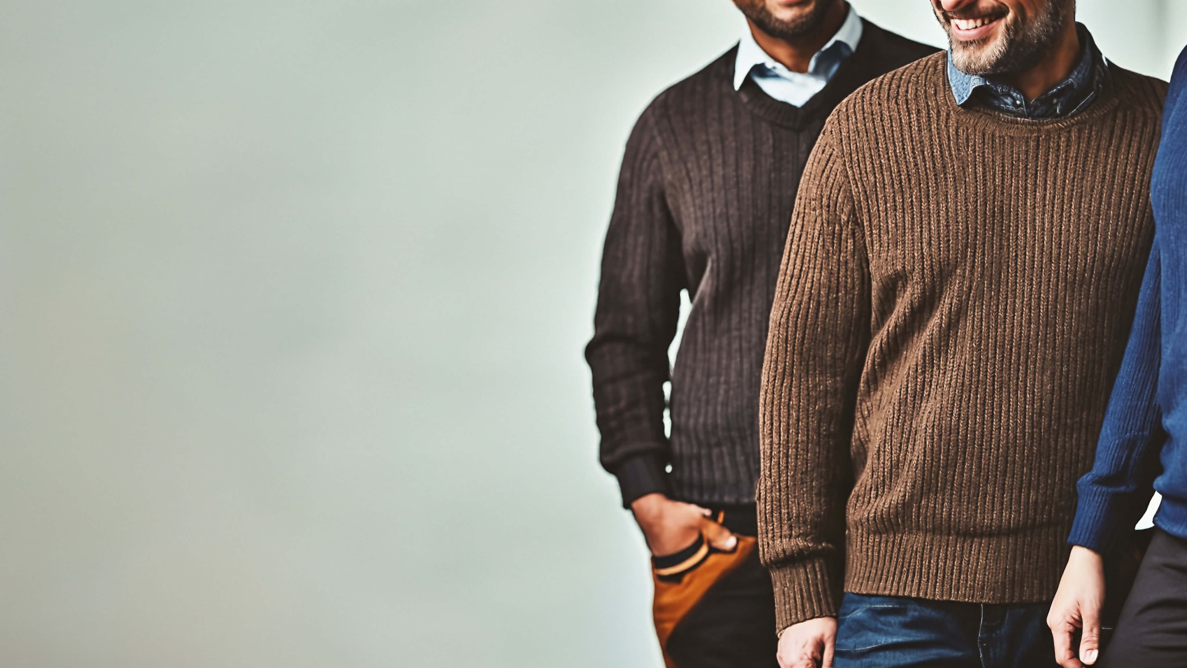 Three people staggered wearing different shades of sweaters.